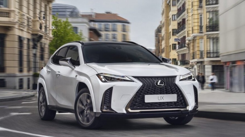 A white 2025 Lexus UX 300h cornering in the city