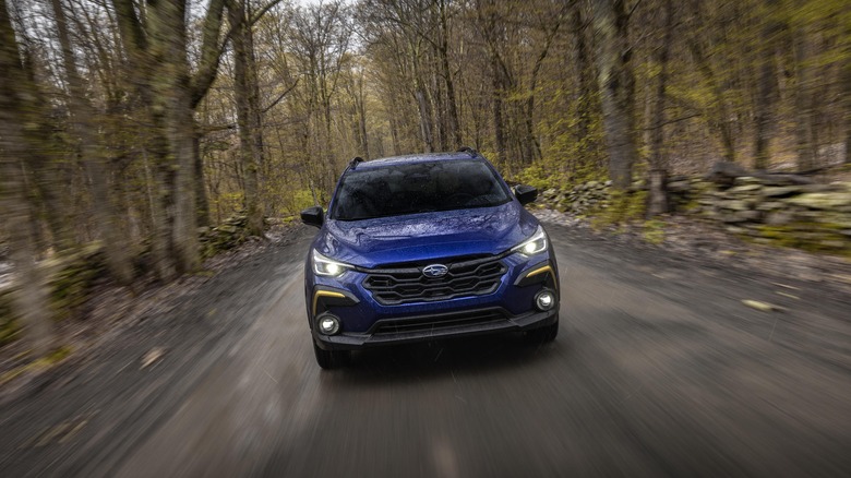 Blue Subaru Crosstrek driving down a forested road