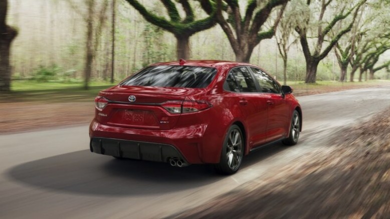 Red Toyota Corolla Hybrid driving on a country road