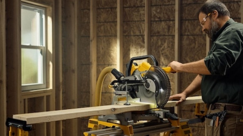 Carpenter using DeWalt miter saw on wood board