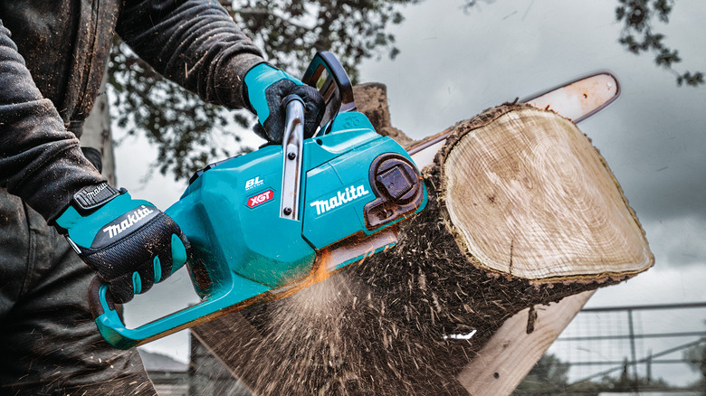 person using a Makita 40V XGT 16-inch chainsaw to cut a log