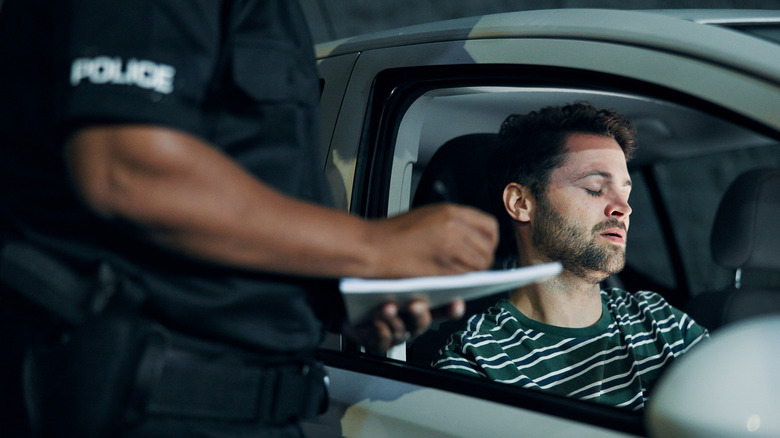 Driver looking disappointed while cop writes ticket.