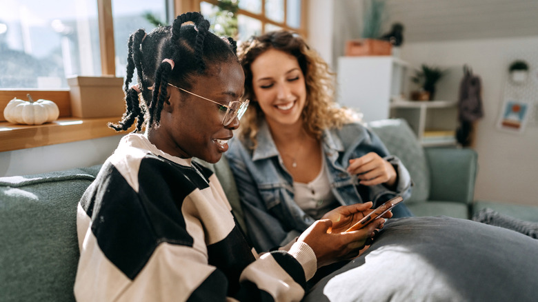 A black and a white women using dating app and smiling