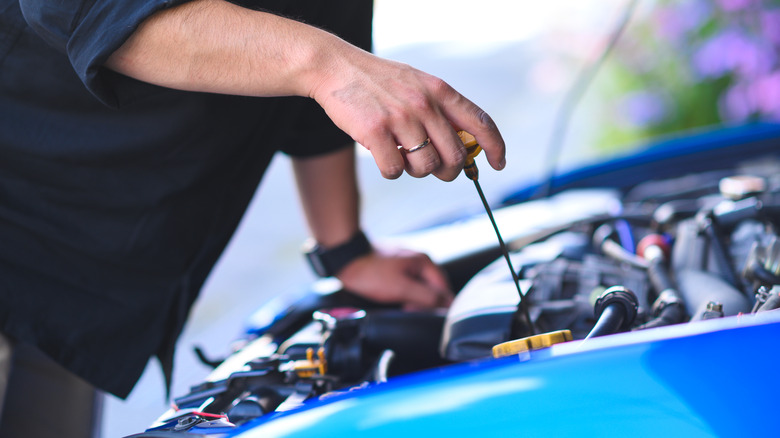 A person using a dipstick to check their engine's oil.