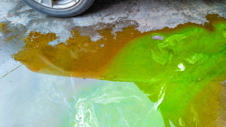 A car leaking coolant and other substances on the ground.