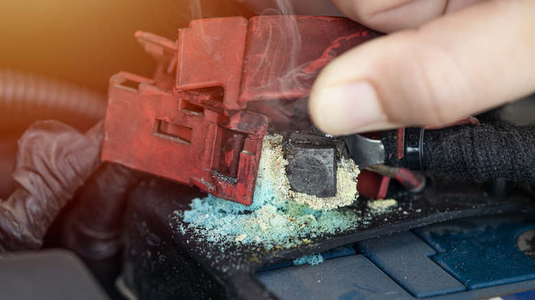 A corroded battery terminal with green blue ash powder on the posts from acid leak