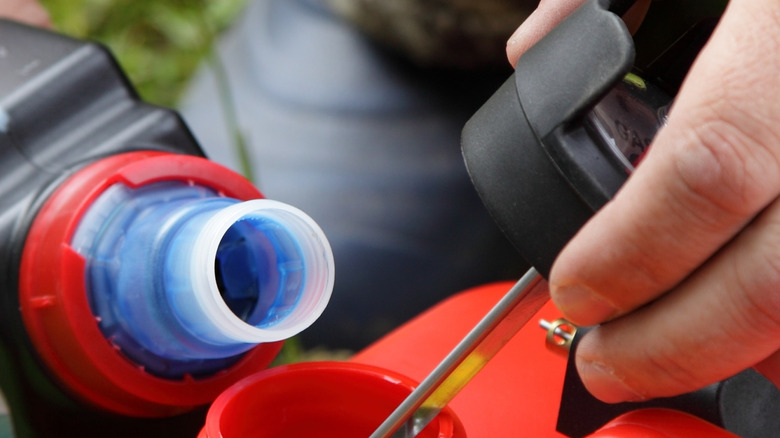 Person adding oil with a cap nearby