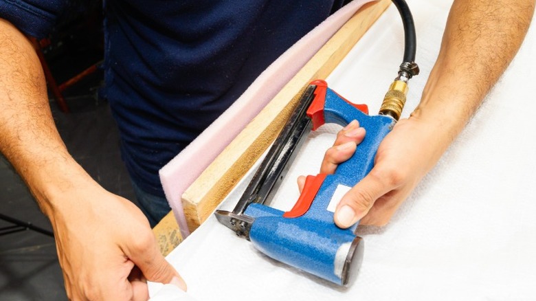 Person using staple gun on wood