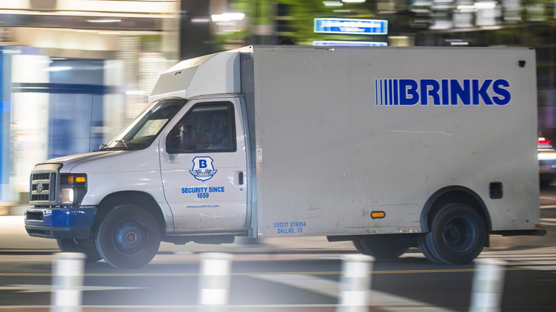 Brinks truck driving down a street at night