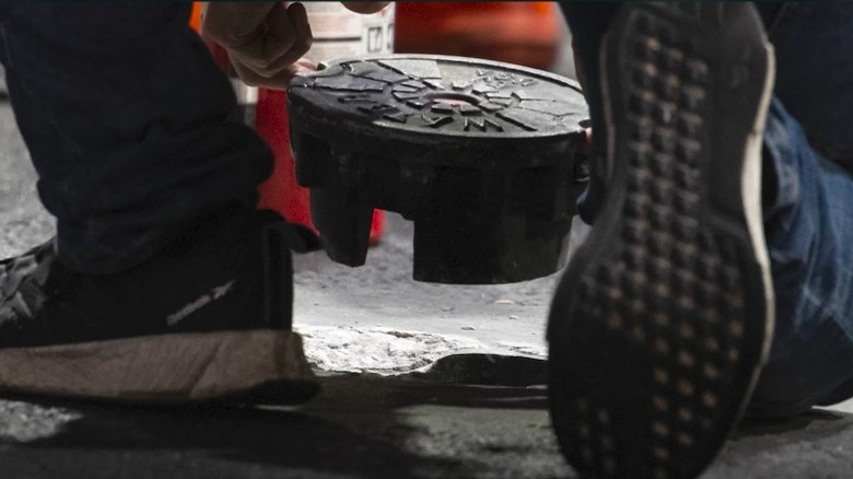 Repai workers lifting manhole