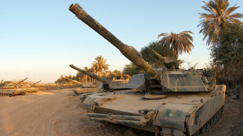 Abrams family tanks on sandy terrain.