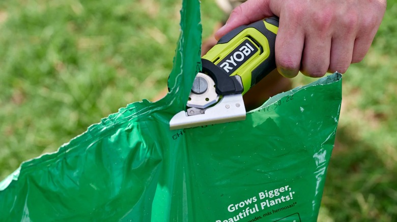Ryobi USB Lithium Power Cutter opening a bag of fertilizer