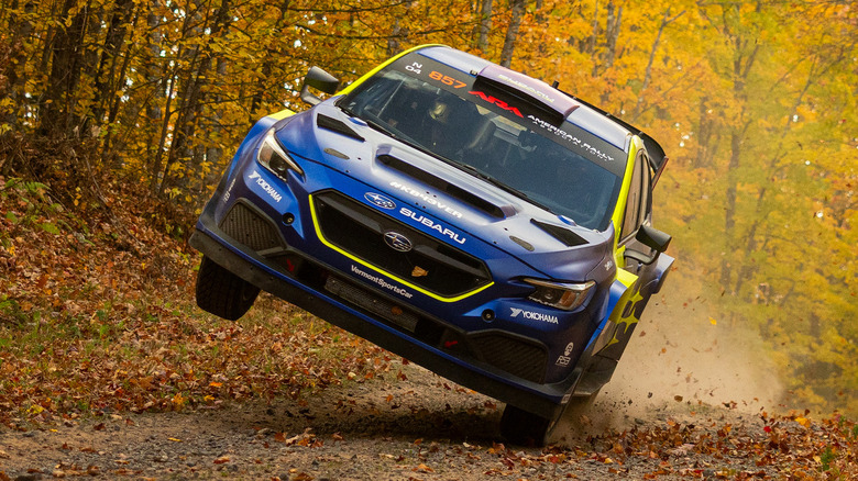 Front view of Subaru rally car up on two wheels with fall foliage