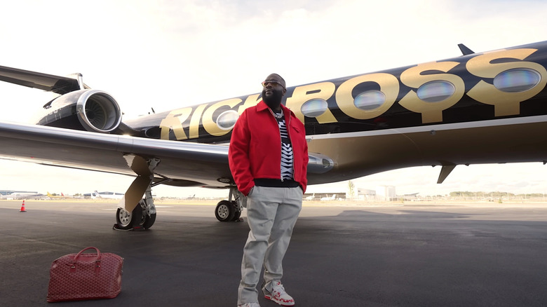 Rick Ross standing in front of his private jet