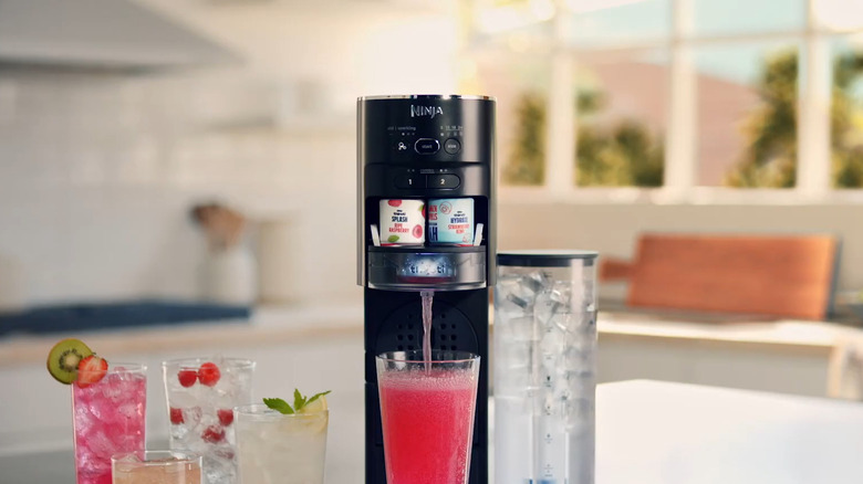 Black Ninja Thirsti making pink soda in kitchen with other drinks next to it