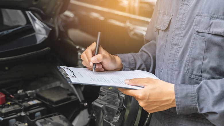 A service technican inspects a vehicle