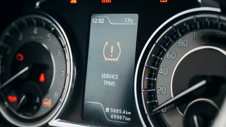 a car dashboard showing the TPMS light and a service warning