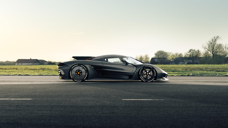 The side profile of a Koenigsegg Jesko Absolut on a runway, black exterior, aero covers on rear wheels