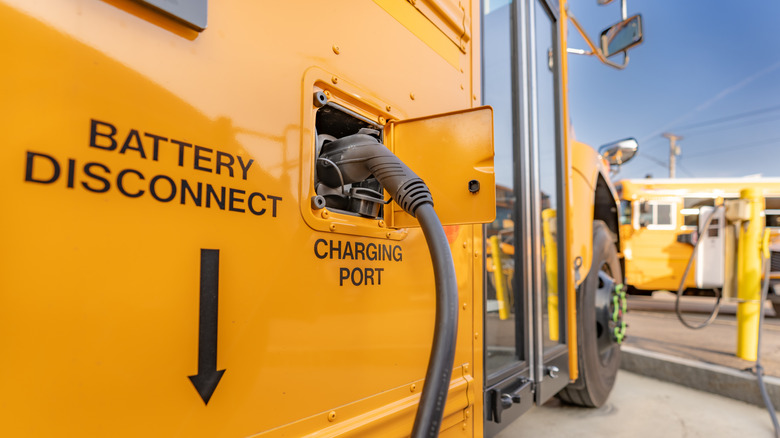 Yellow electric school bus plugged in at a charging station