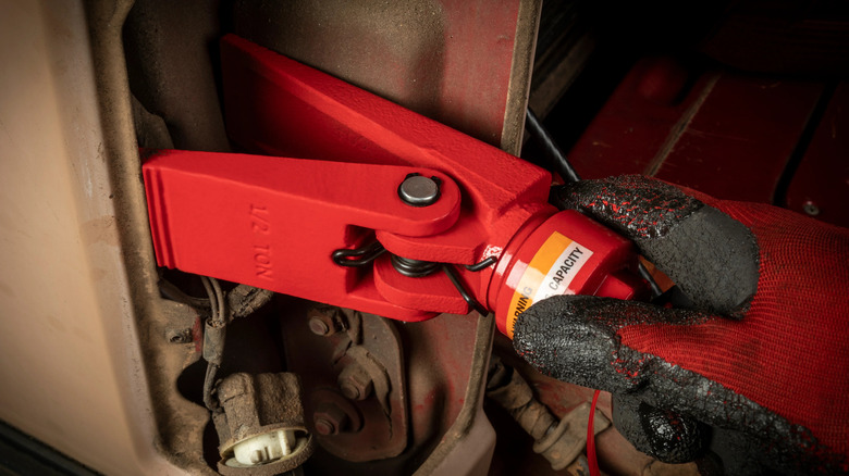 Hand holding hydraulic power kit with claws wedged into auto door frame