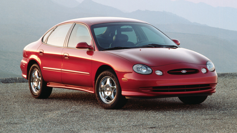 1996 Ford Taurus parked on an asphalt surface with mountains in the background
