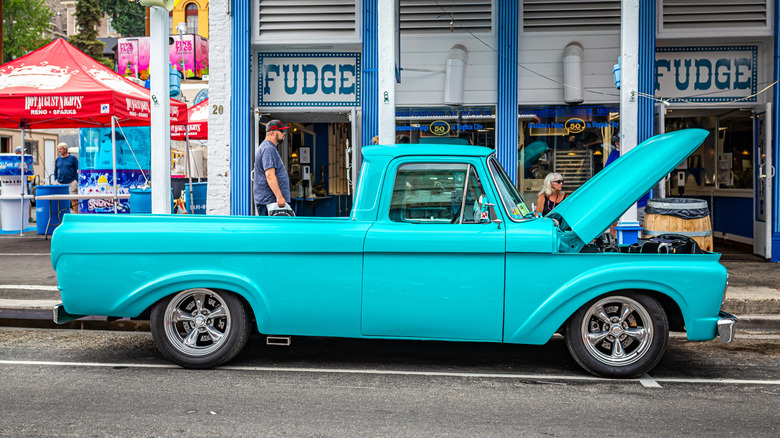 blue Ford F-100 1961 model parked near the sidewalk