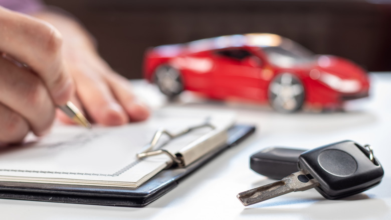 Man signs car insurance document with car keys