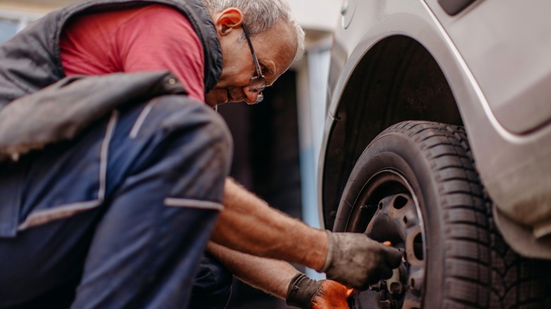 A person installing lug nuts after performing a tire rotation