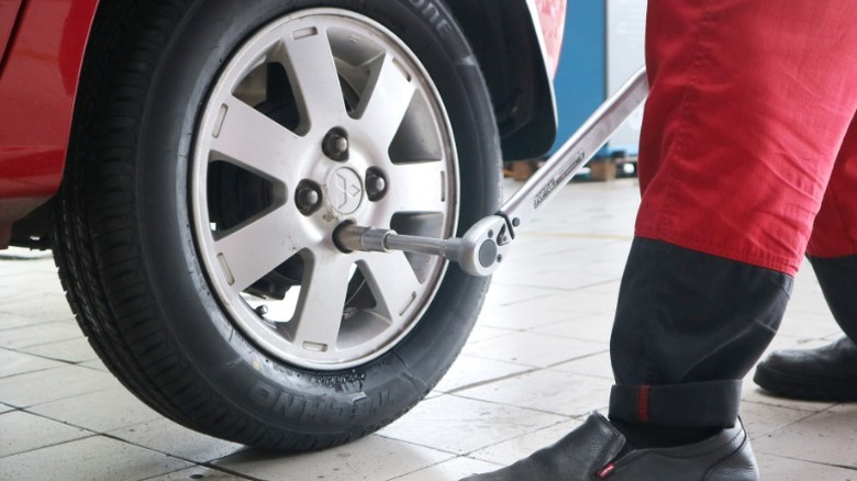 A person using a torque wrench to tighten lug nuts properly