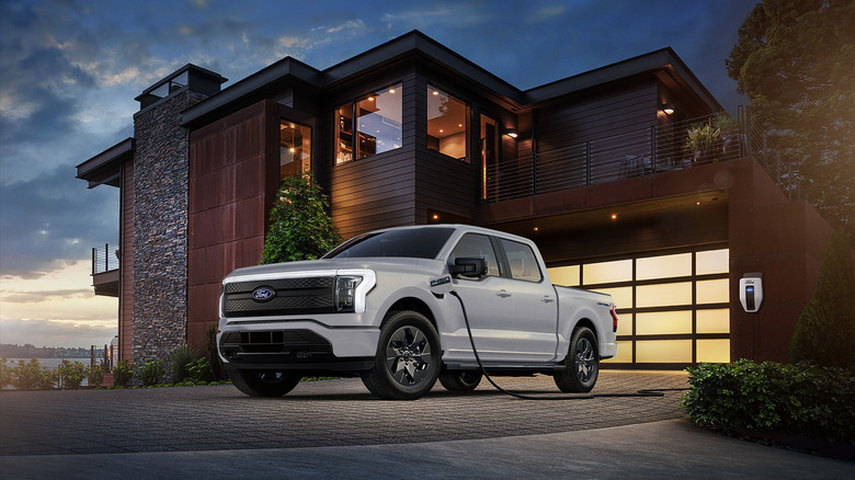 A white Ford F-150 Lightning powering a home, front 3/4 view