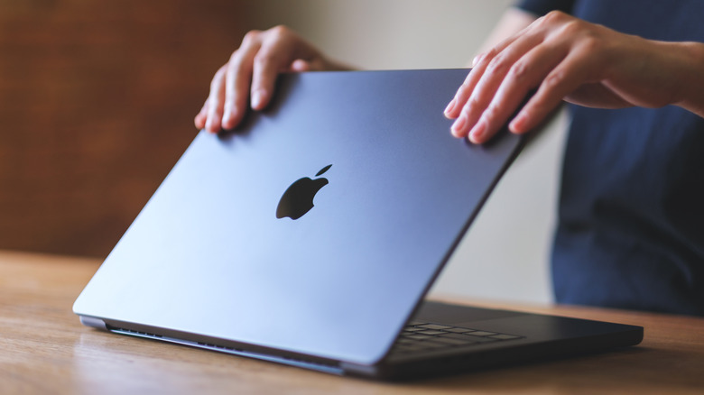 A woman opening or closing an Apple MacBook Pro laptop