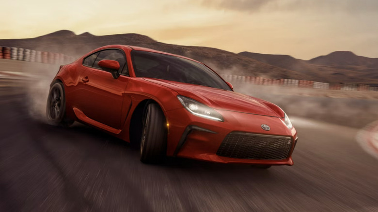 Toyota GR86 drifting on a paved racetrack with hills in the background