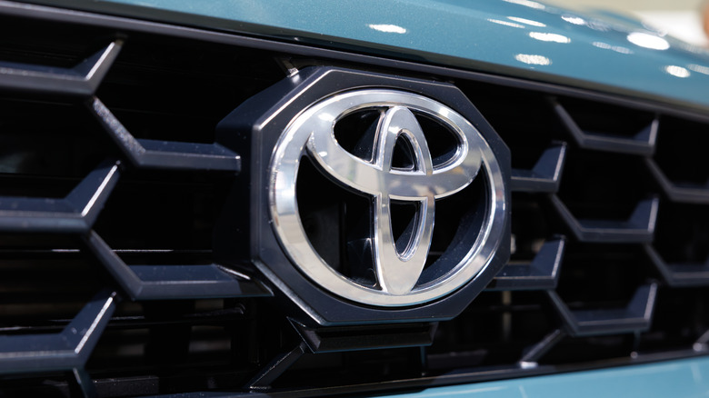 A close-up of a Toyota badge on an unidentified blue Toyota