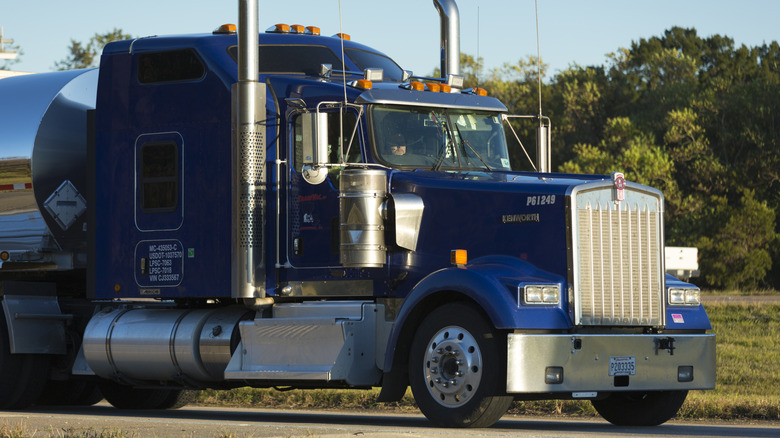 Front 3/4 quarter view of a blue axle-forward Kenworth truck, with a tanker attached