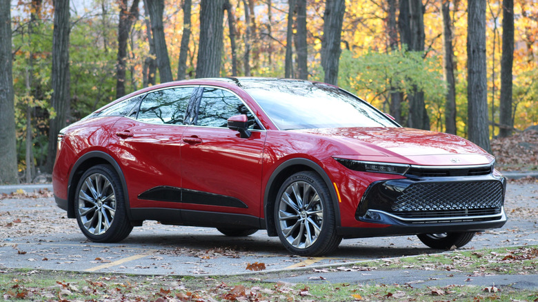 Red Toyota Crown parked with a forest in the background