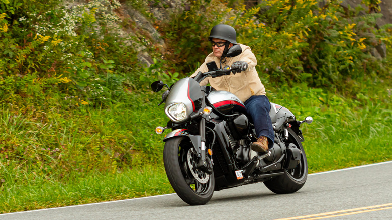 Male rider in tan jacket riding a Suzuki Boulevard M109R in silver with red trim