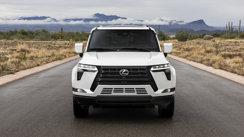 Front view of white Lexus GX parked in the middle of a desert road.