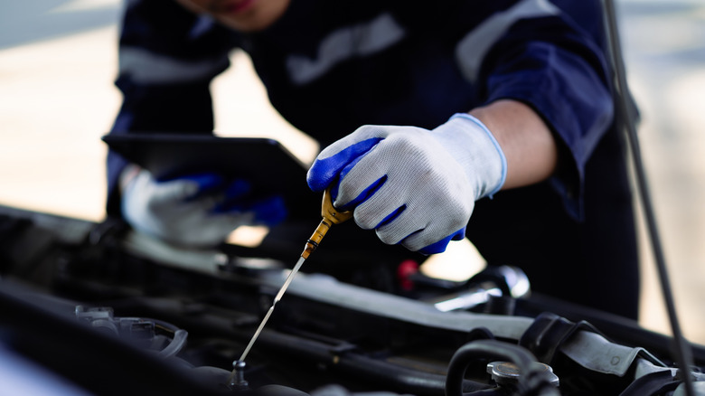 Mechanic checking oil level using a dipstick