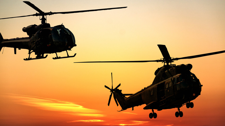 Silhouette of combat helicopters at sunset in the sky