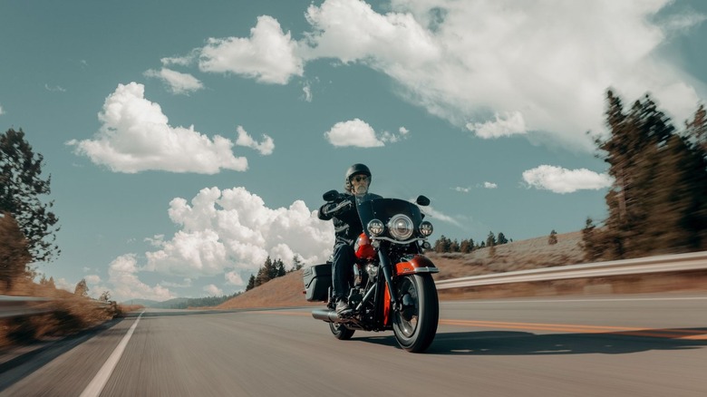 Biker rides red Heritage Classic down a highway