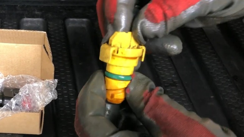 A person holding a plastic oil drain plug.