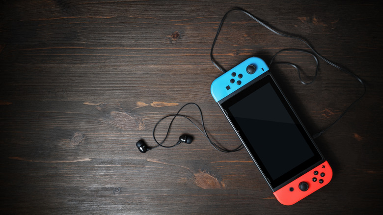 Nintendo Switch and wired earphones on a wood surface