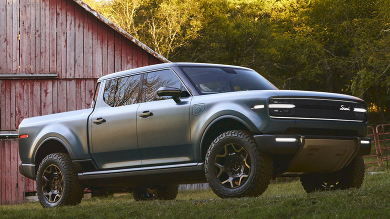 Green Scout Terra pickup truck parked in grass outside red barn
