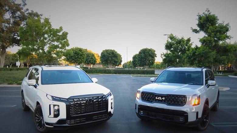 A White 2024 Hyundai Palisade parked next to a White 2024 Telluride in an empty lot.