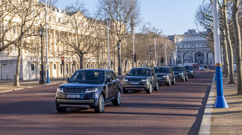 A line of Range Rovers moving down a road in the UK as part of a showroom opening parade.