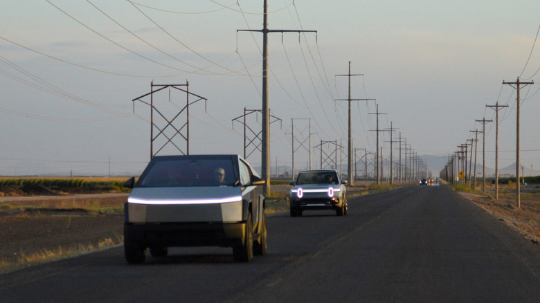 A Tesla Cybertruck and Rivian vehicle driving together on a rural road in the evening.