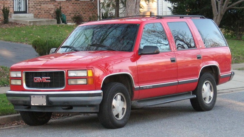 A red GMC Yukon parked outside a brick house