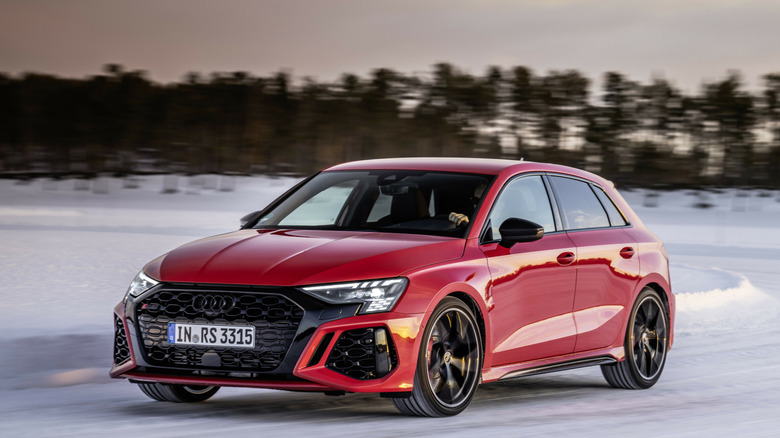 A red car being driven in a winter scene