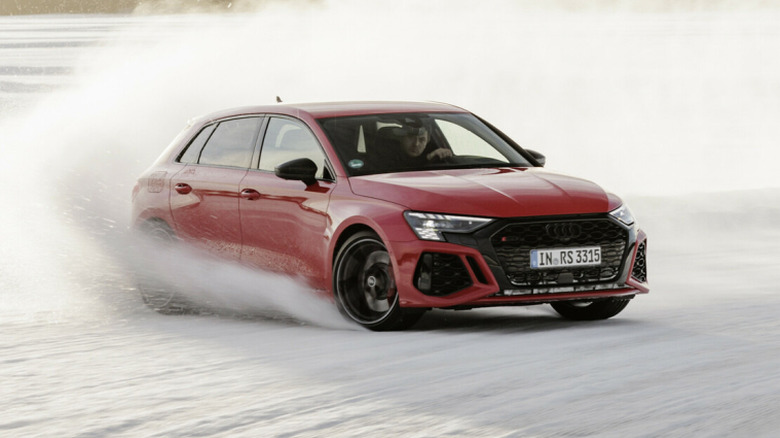 A red Audi car plows through a snowy turn