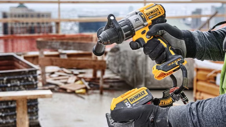 Construction worker holding 20V MAX XR Brushless 3-Speed ½-inch Hammer Drill/Driver and battery